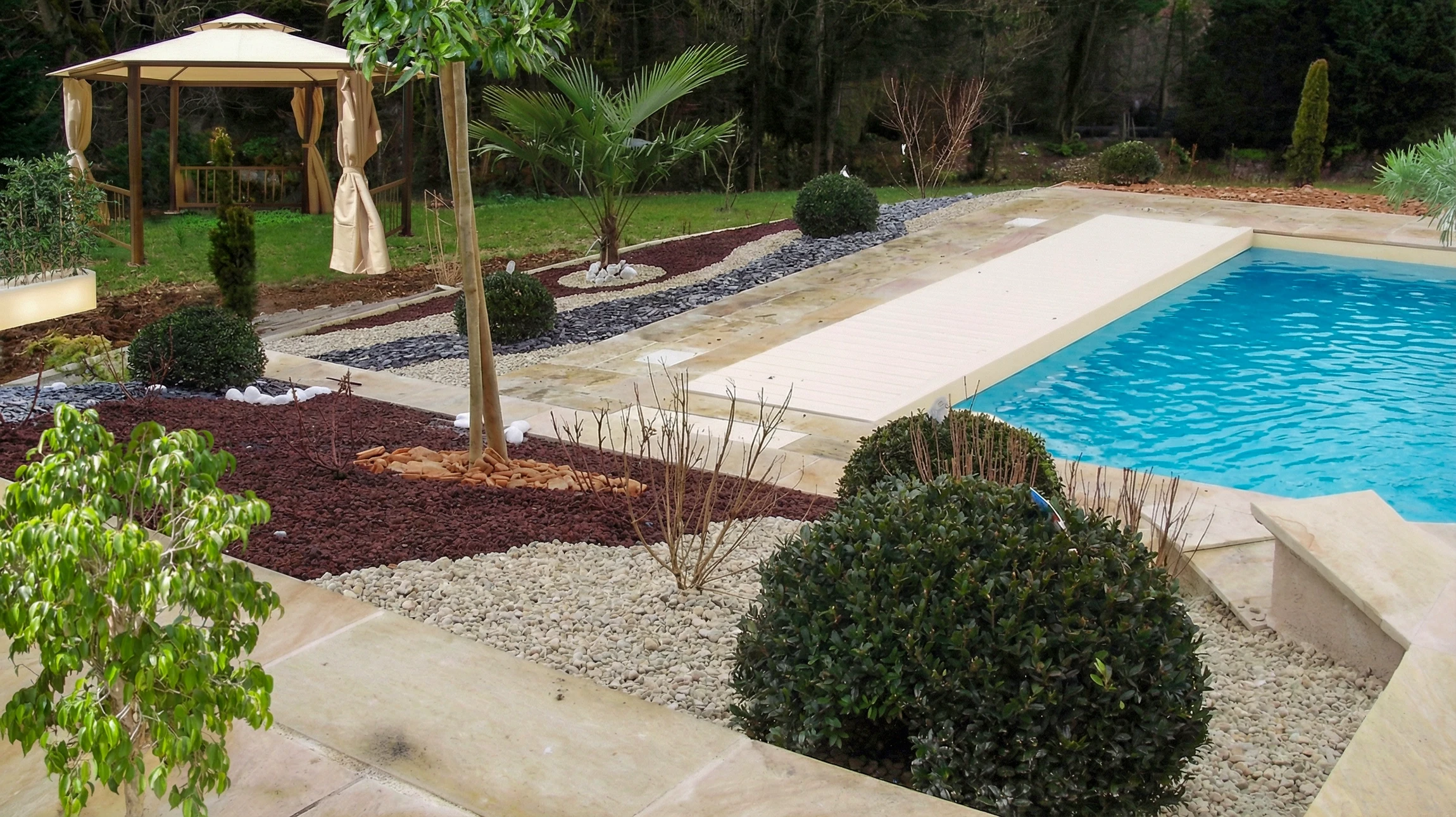 Terrasse en bois avec salon de jardin face à un bassin aquatique aménagé